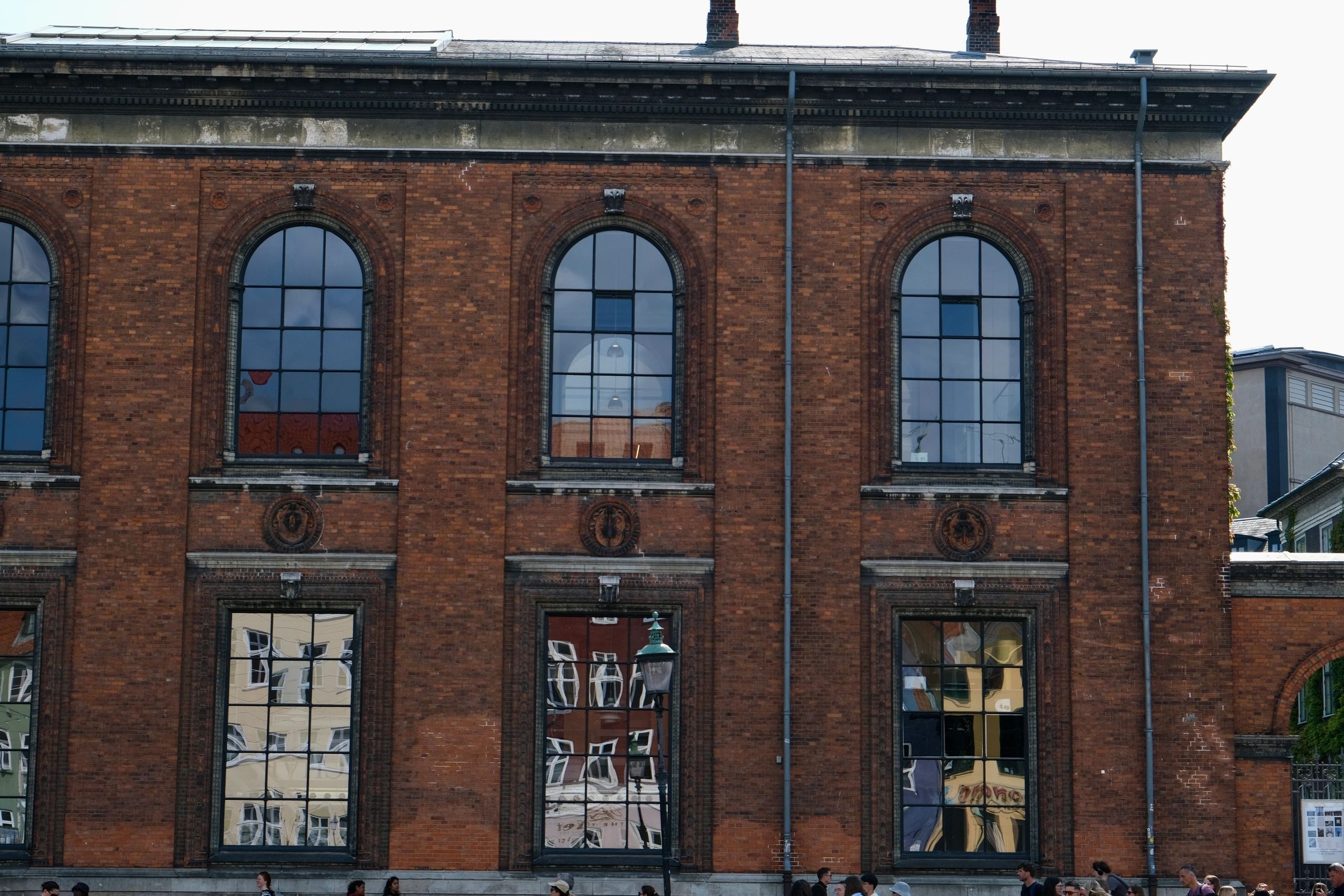 Red-brick building facade with tall arched windows in Copenhagen