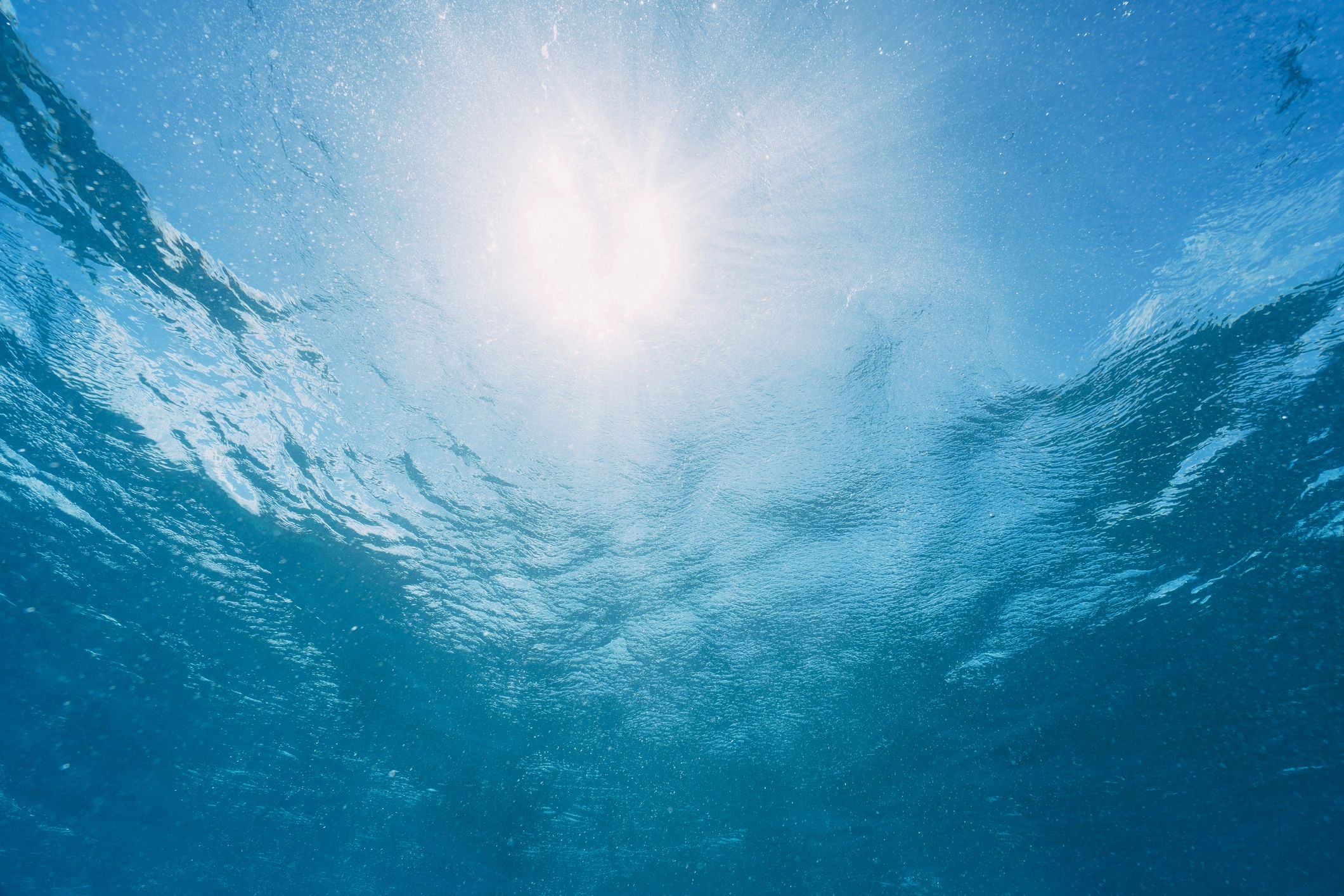 Sunlight penetrating the clear ocean surface from an underwater perspective, creating a vibrant blue background